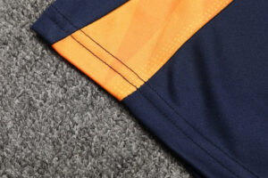 Close-up of navy fabric with an orange stripe and visible stitching on a gray carpeted surface.