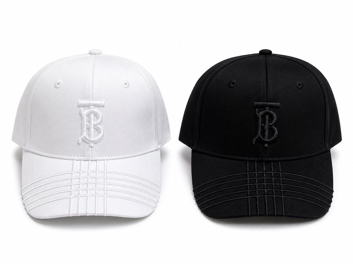Two baseball caps facing forward: one white and one black, each with a stitched TB monogram on the front.