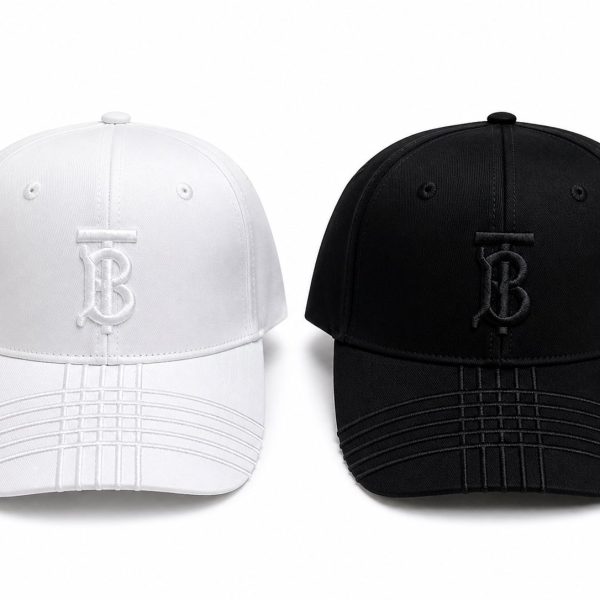 Two baseball caps facing forward: one white and one black, each with a stitched TB monogram on the front.