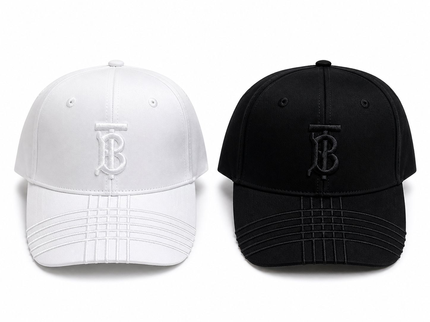60ed3d96-bb17-4129-a5ec-240531adafd5 Two baseball caps facing forward: one white and one black, each with a stitched TB monogram on the front.