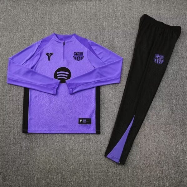 Purple Barça-style long-sleeve training top with black side panels and crest, paired with black pants featuring a purple crest on a gray carpet.