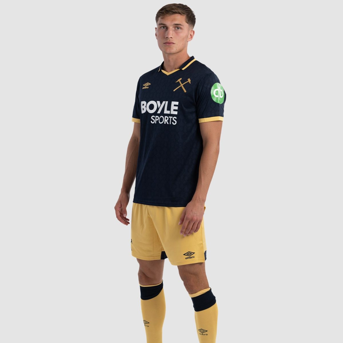 Male soccer player wearing a navy jersey with yellow trim and Boyle Sports logo, posing in a neutral stance with yellow shorts and socks.