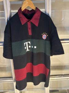 Dark color-block polo dress with a maroon collar, green mid-band with a large white logo, and a Bayern Munich crest on the chest.