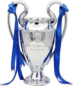 Silver trophy cup with blue ribbons draped from its handles on a white background.