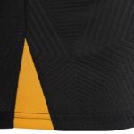 Close-up of black fabric with an orange triangular stripe and visible stitching details on the edge of the garment.