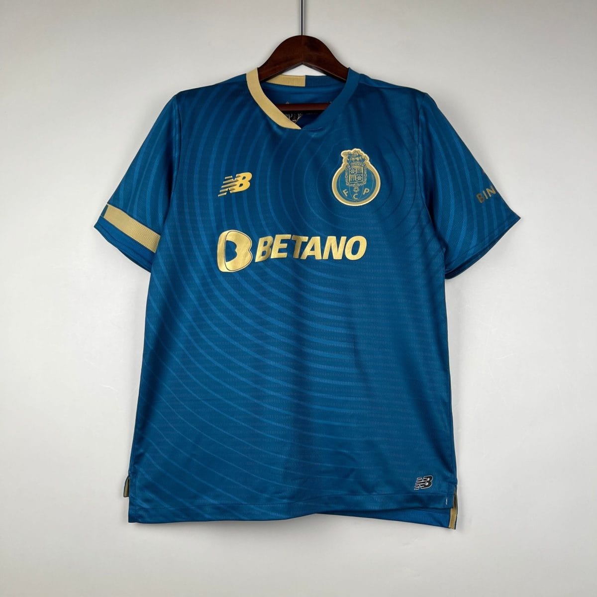 Blue soccer jersey on a hanger, featuring a gold-trimmed collar, crest on the chest, and Betano logo across the front.