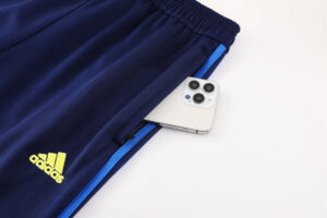 6310f61e | UAE SPORT STORE Navy Adidas track pants with a bright yellow logo, zipper pocket holding a white iPhone partially inside the pocket.