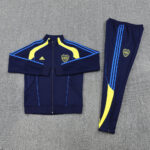 632150b5 | UAE SPORT STORE Navy blue athletic tracksuit with yellow and blue piping, zip-front jacket and matching pants, featuring an Adidas logo and a CABJ crest on the chest and leg.