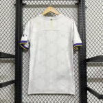 White short-sleeve shirt on a wooden hanger, featuring a faint repeating pattern and purple-yellow trim on the sleeve cuffs, displayed on a metal rack.
