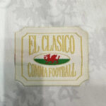 Embroidered patch reading 'EL CLASICO' with a red dragon in a green oval on beige fabric