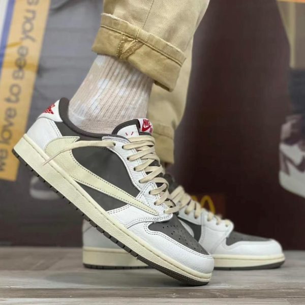 White and gray Nike sneakers with beige accents and cream laces on a wooden floor; cuffed tan pants visible at the ankle.