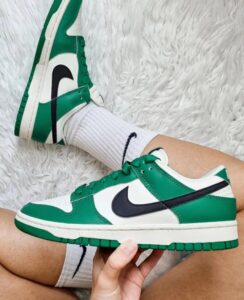 Green and white Nike sneakers with a black swoosh, shown on a leg wearing white socks.