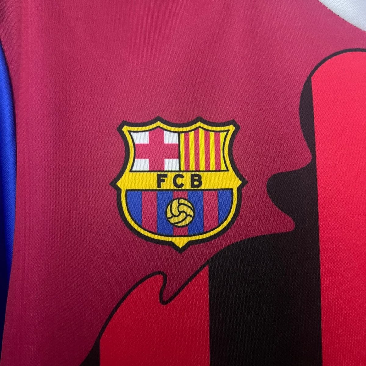 Close-up of a red FC Barcelona jersey showing part of the club crest and a blue stripe along the side.