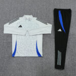 Light gray leopard-print athletic top with blue panels and a zip collar, paired with black track pants that have a blue stripe and logo.