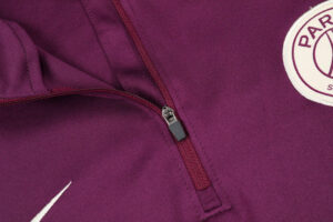 Close-up of a maroon jacket zipper with a circular patch and a white swoosh logo.