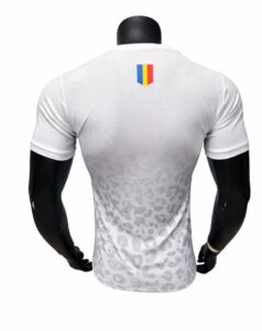 Back view of a white athletic jersey with a subtle grey leopard-like pattern and a small vertical tricolor shield on the upper back.
