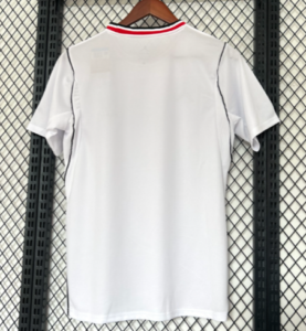 White short-sleeve T-shirt hanging on a hanger, viewed from the back, on a metal grid background.