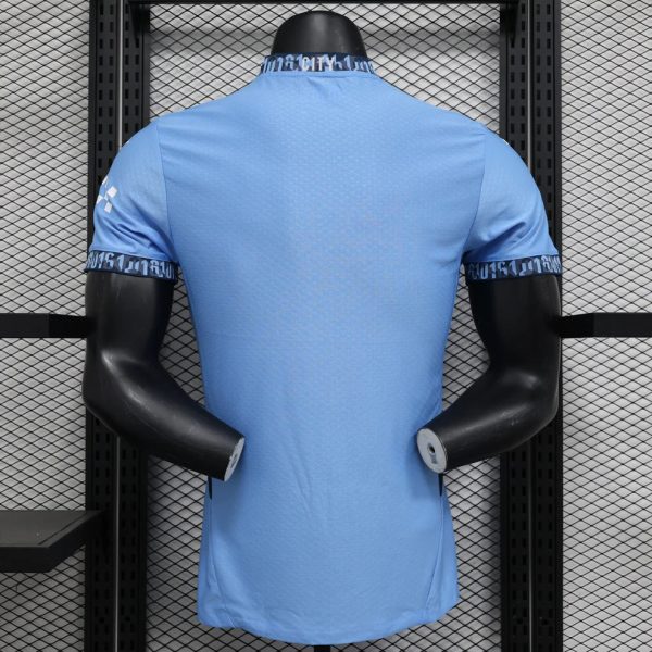 Back view of a light blue athletic jersey on a black display mannequin against a metal grid wall.