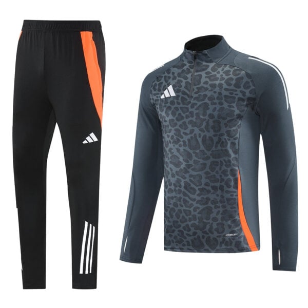 Two-piece adidas athletic tracksuit: black joggers with an orange side stripe and a white logo, paired with a dark gray leopard-print long-sleeve top featuring orange accents.