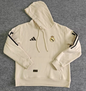 Cream-colored Real Madrid hoodie laid flat with hood, drawstrings, a front kangaroo pocket, Adidas logo, and Real Madrid crest on the chest.