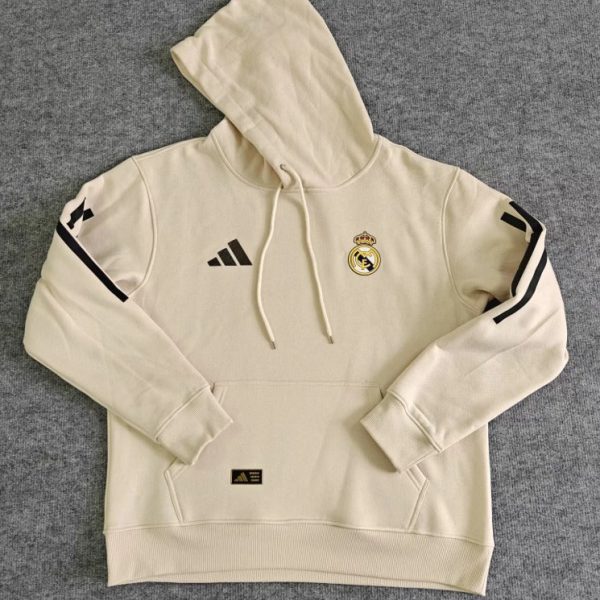 Cream-colored Real Madrid hoodie laid flat with hood, drawstrings, a front kangaroo pocket, Adidas logo, and Real Madrid crest on the chest.