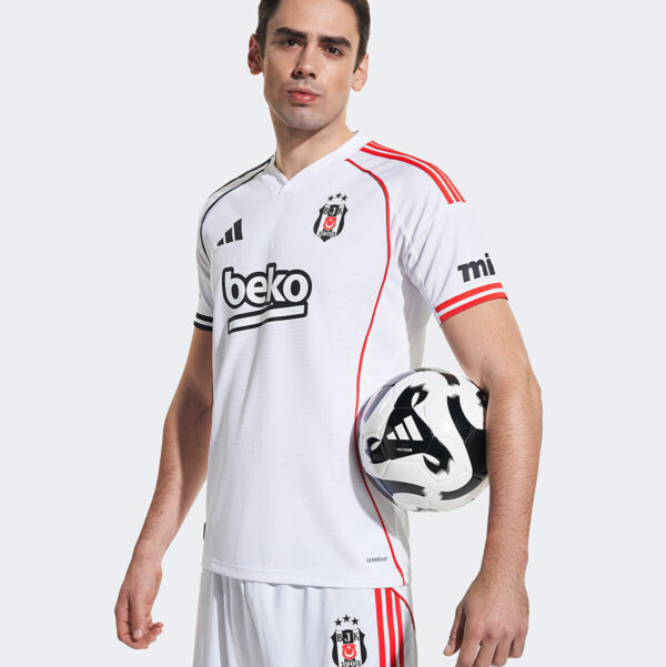 Male soccer player in a white Beşiktaş jersey holding a black-and-white soccer ball against a light background, showing the team crest and sponsor logo.
