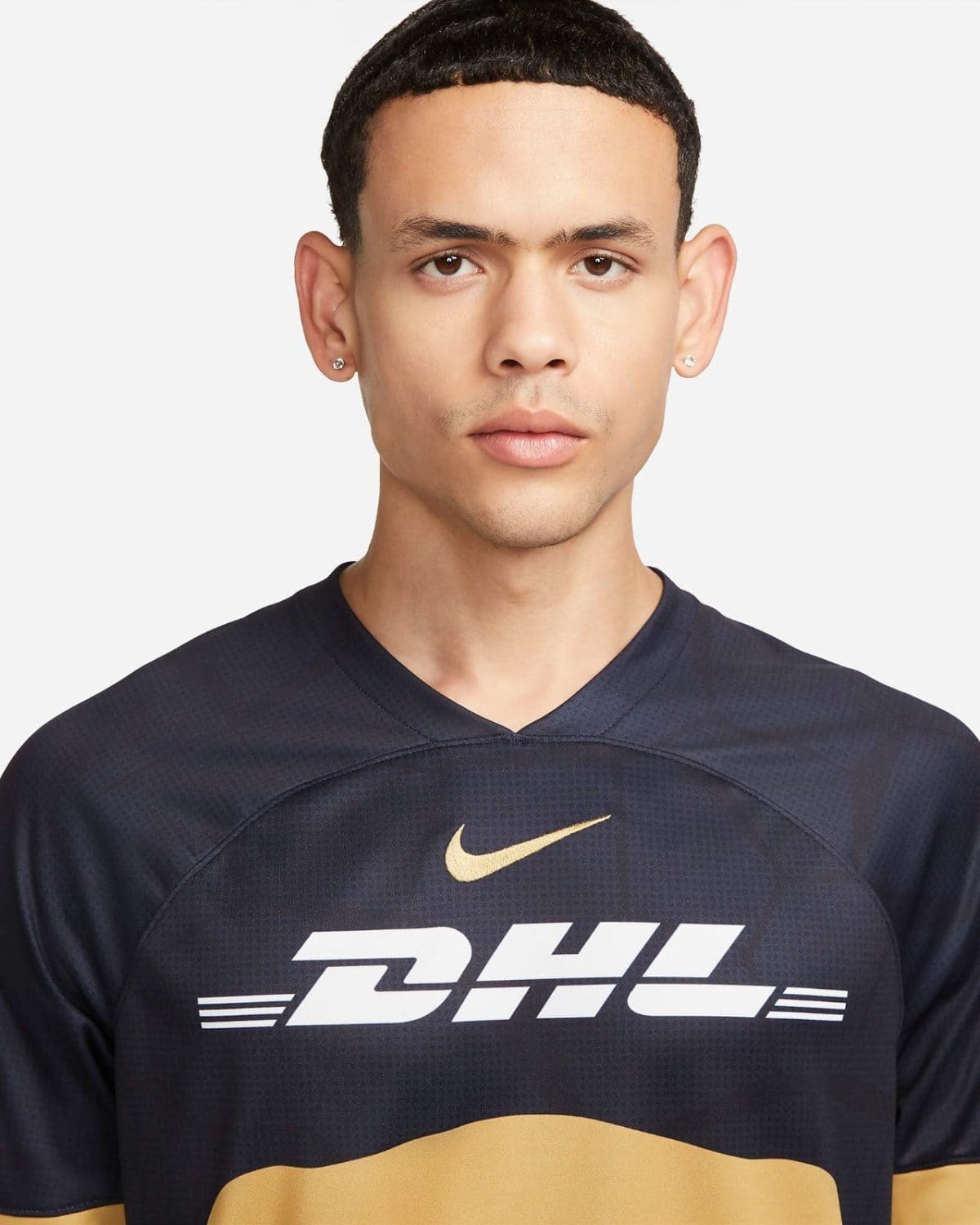 Close-up portrait of a young man wearing a black athletic shirt with white DHL lettering and a gold Nike swoosh.