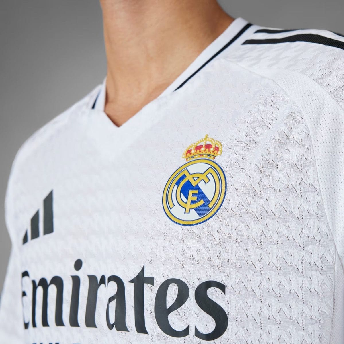 Close-up of a white Real Madrid jersey showing the club crest and part of the Emirates sponsor text.