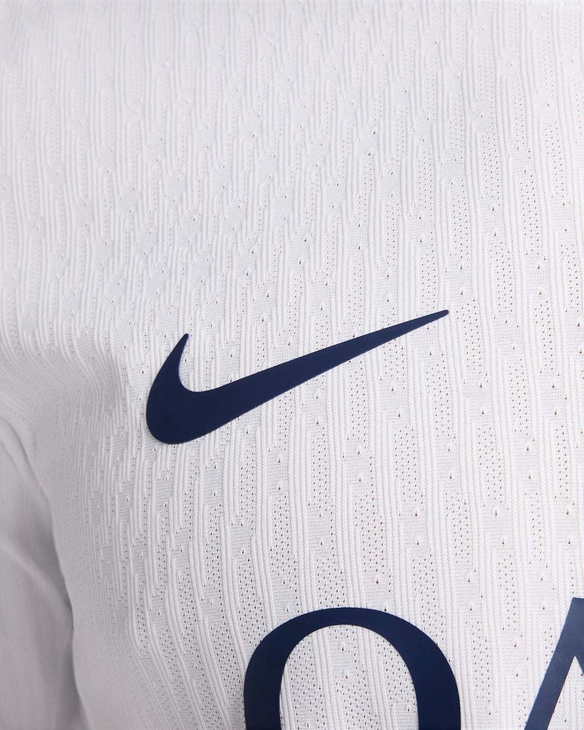 Close-up of a navy Nike swoosh on a white textured sports jersey.