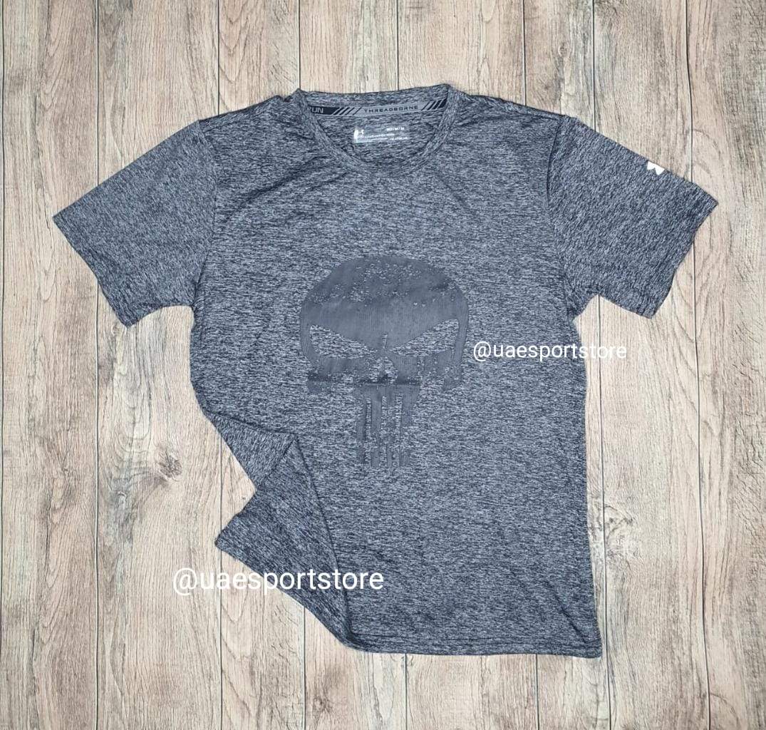 6a0fc32a-456d-4570-a2f5-5e592e7c22ee_1_591130f0-c6a9-4e07-ab0e-ec9abd907eb4 | UAE SPORT STORE Heather gray short-sleeve crew-neck T-shirt laid flat on a wooden floor, featuring a large dark skull graphic in the center.