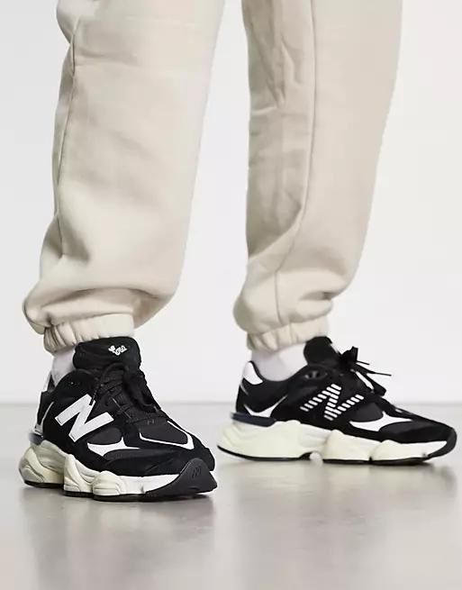 Person wearing beige joggers and black-and-white sneakers standing on a light floor, front view showing the shoes' details.