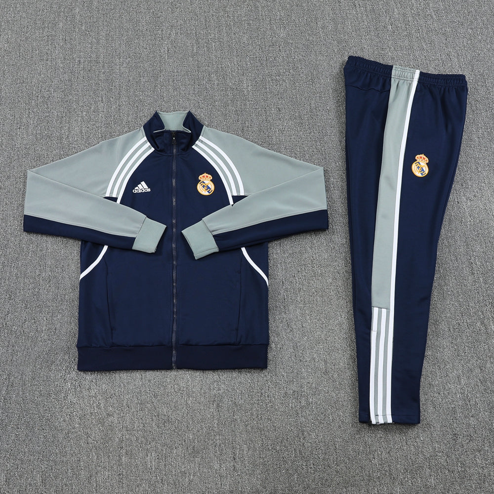 6ac0e3ae | UAE SPORT STORE Real Madrid navy and light gray tracksuit jacket and matching pants laid flat on a gray carpet.