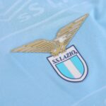 Golden winged-eagle Lazio emblem above the club crest on a light blue jersey.