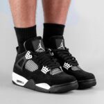 Black and white basketball sneakers with Jumpman logo on the tongue, worn with black crew socks.