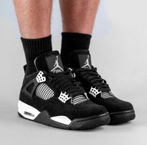 Black and white basketball sneakers with Jumpman logo on the tongue, worn with black crew socks.