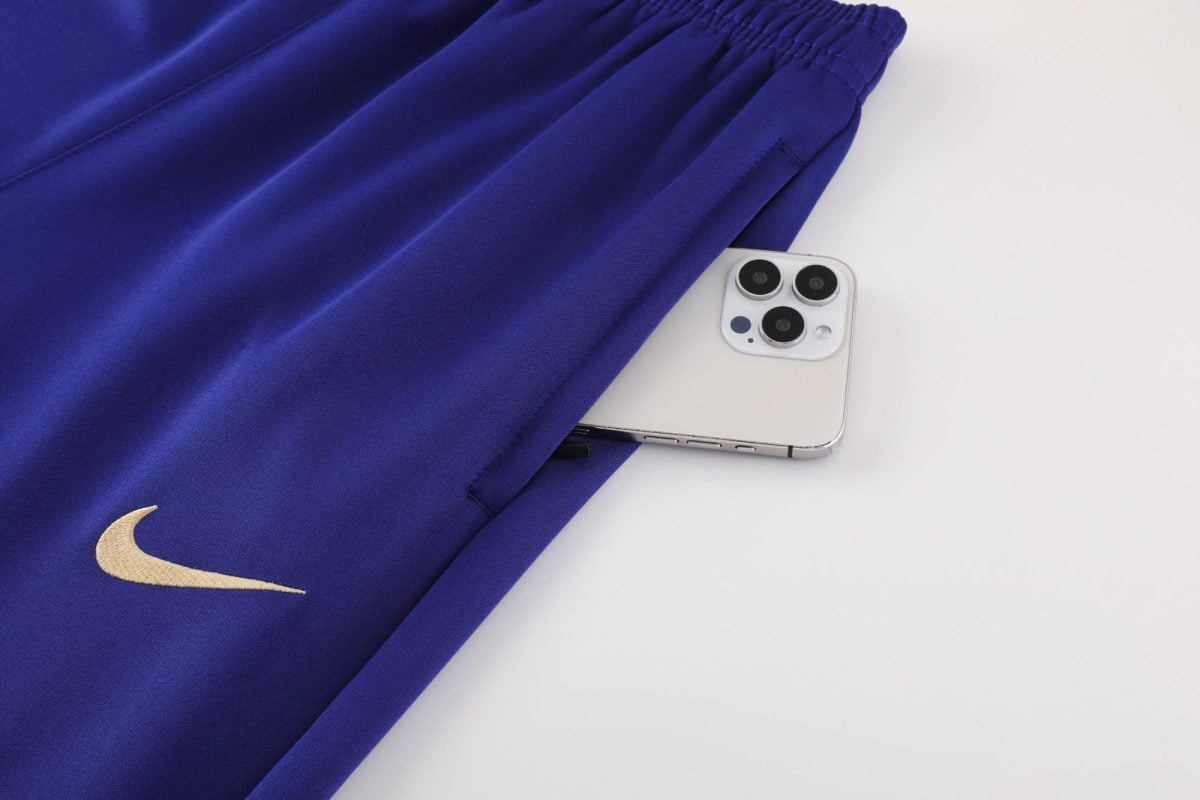 Blue Nike hoodie draped over a white surface with a white iPhone partially tucked underneath.