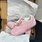 Pink New Balance sneakers in an open shoebox, laced and resting on tissue paper.