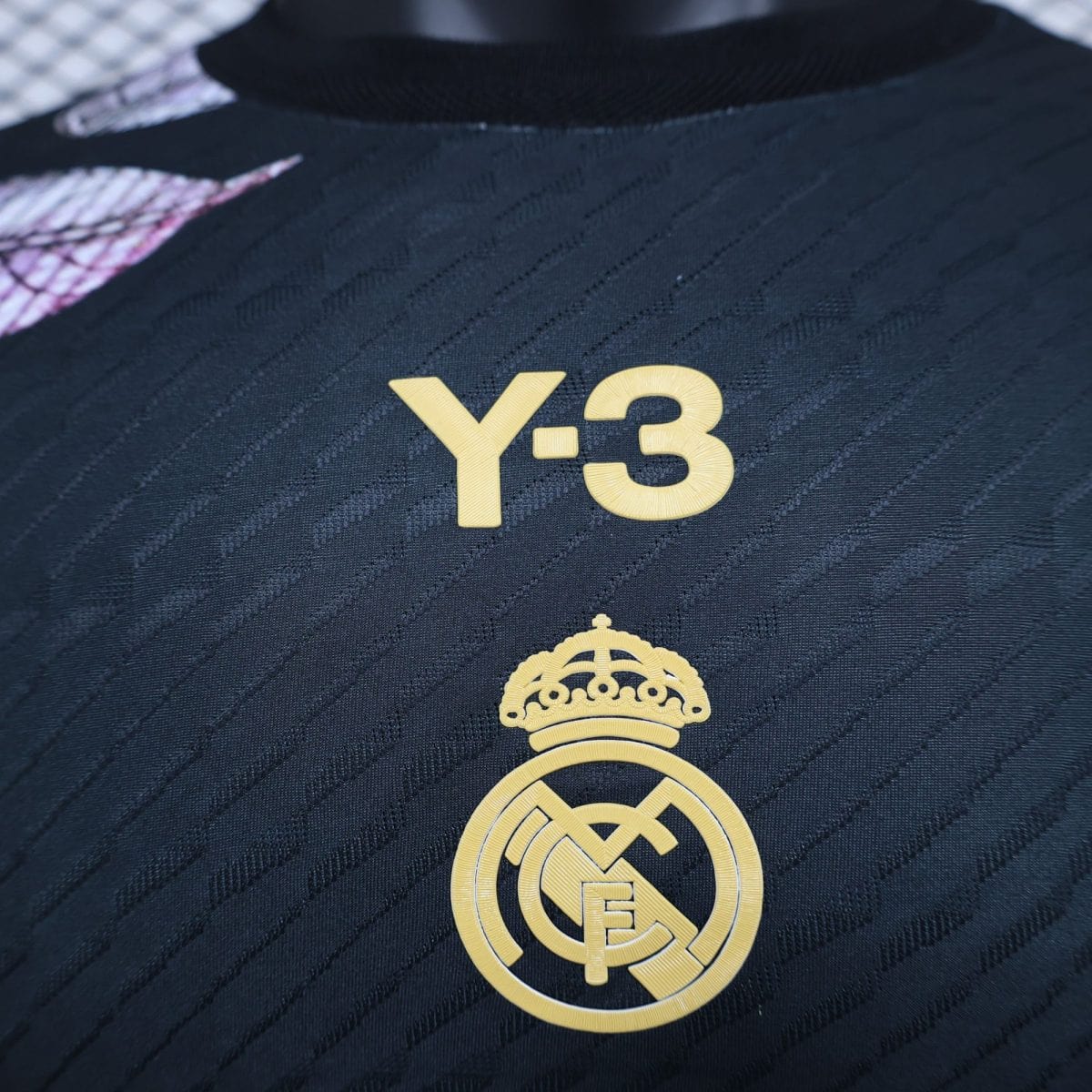 Close-up of a dark jersey with a gold Real Madrid crest embroidered near the bottom.