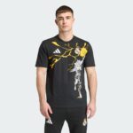 6cad08b1-9296-4dec-90bc-635d840f0ead | UAE SPORT STORE Man wearing a black Real Madrid graphic t-shirt with yellow lightning design and white Adidas logo, standing against a pale gray background.