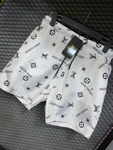White Louis Vuitton shorts with allover black logo pattern, hanging on a hanger.