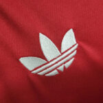 White Adidas trefoil logo on red fabric (close-up)