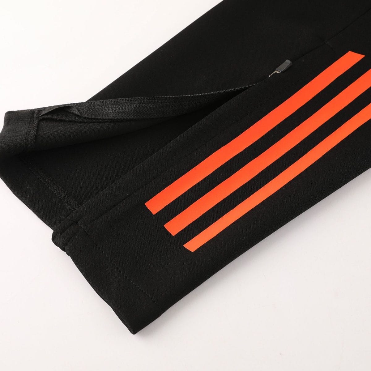 Close-up of black fabric with three bright orange diagonal stripes and a small zipper pull.