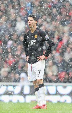 6da3fac08a99a4d9c7137d83a17c581b-manchester-united-chelsea-manchester-united-players_1283b536-7426-4100-9028-d5af0224f277 | UAE SPORT STORE Cristiano Ronaldo standing on a snowy, rain-soaked football pitch in a Manchester United kit with number 7 and AIG sponsor, hands on hips.