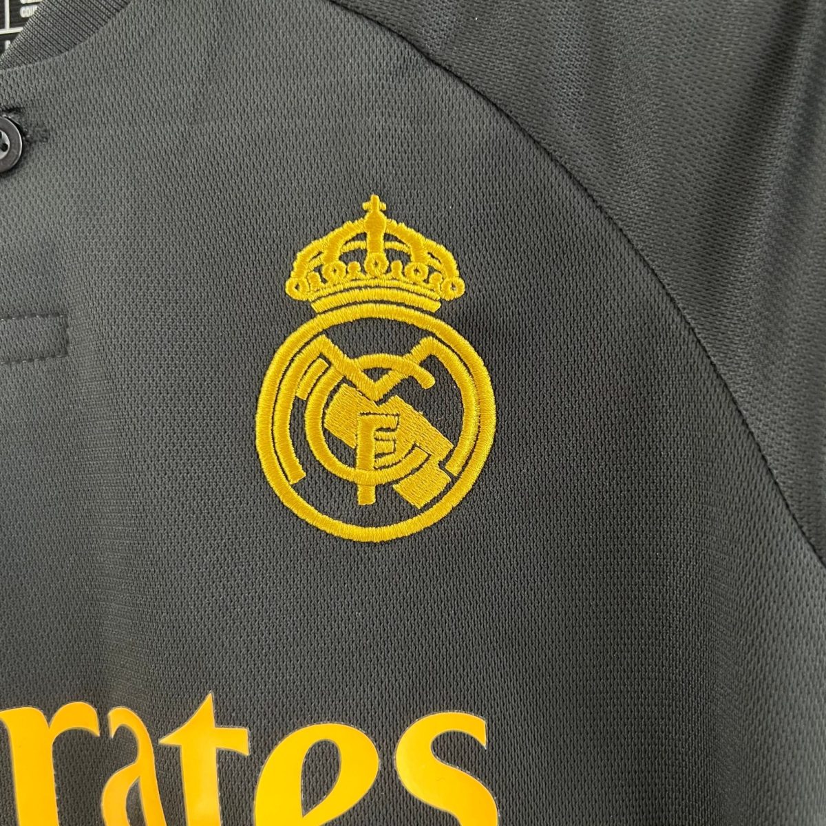 Close-up of gray fabric with ornate yellow crown embroidery.
