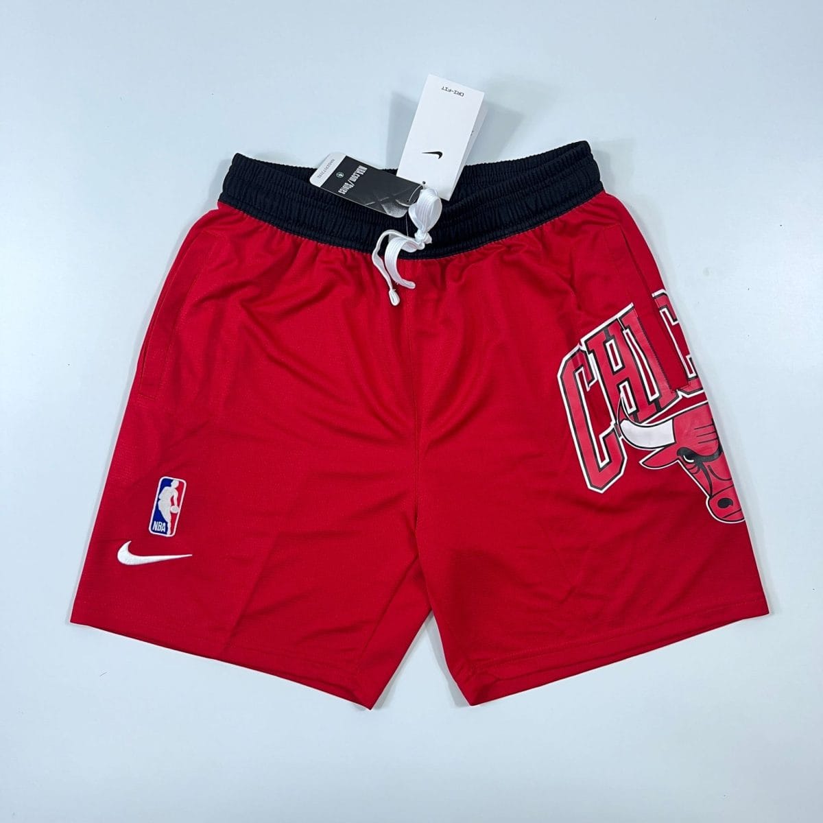 Red basketball shorts with a black waistband, white drawstring, featuring an NBA logo patch and a large Bulls graphic on the right leg.