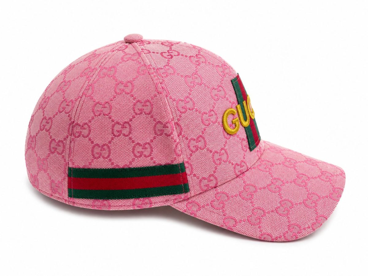 Pink Gucci baseball cap with all-over GG monogram, green-red-green web strap and yellow 'GUCCI' logo on the front.