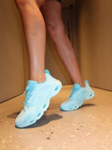 Close-up of a person wearing light blue running shoes as they walk down a hallway.
