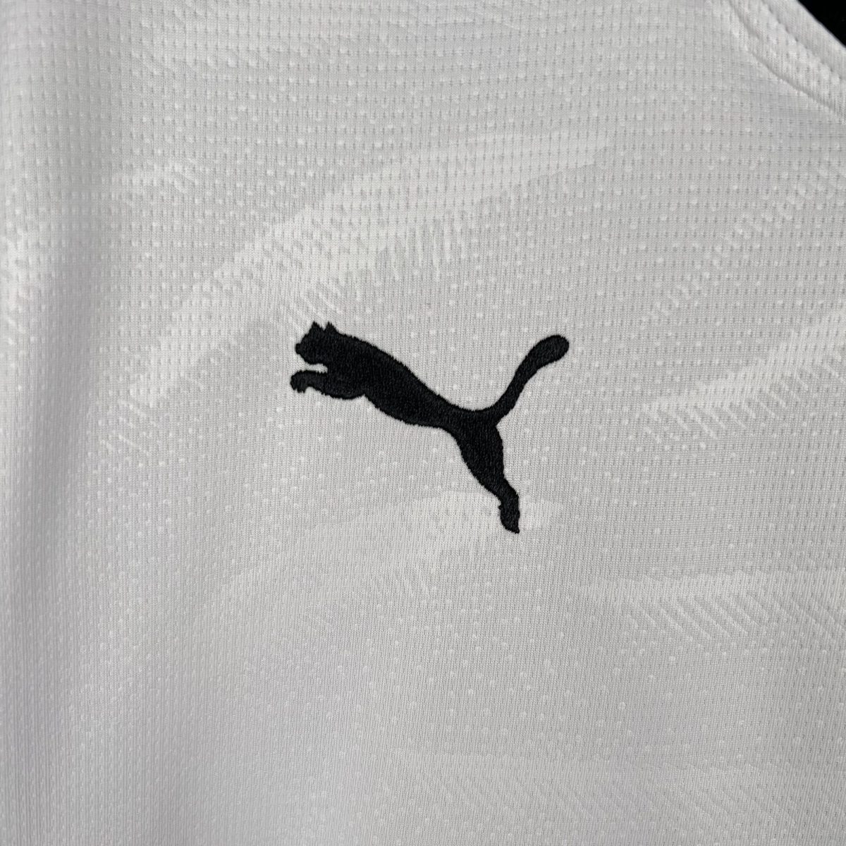 Close-up of white textured fabric with a partial black Puma logo silhouette visible.