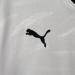 Close-up of white textured fabric with a partial black Puma logo silhouette visible.