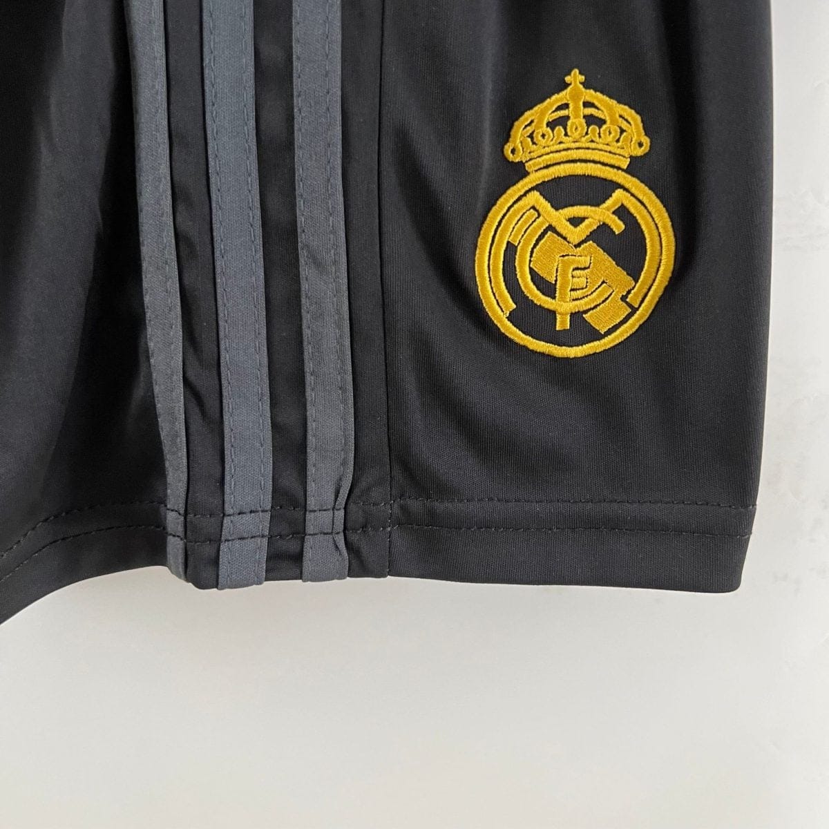 Close-up of dark fabric with a gold Real Madrid crest embroidery.